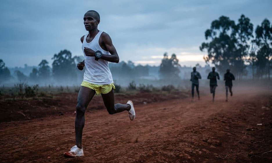 Coureur élite kenyan en pleine foulée sur piste dorée